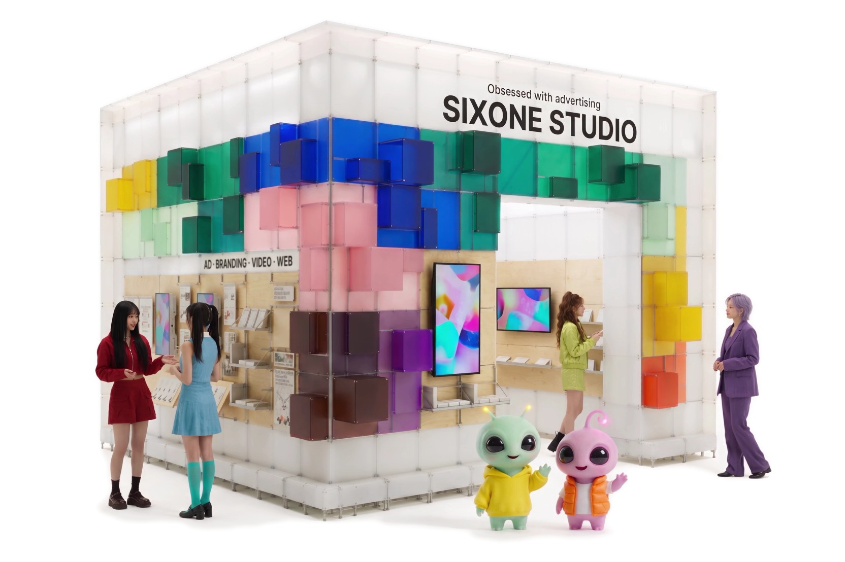 색색의 큐브로 지은 SIXONE STUDIO 팝업 부스 앞에 선 사람들과 식스원 캐릭터 두 명(노란 후드티의 연두색 외계인 · 주황 조끼의 분홍색 외계인)
